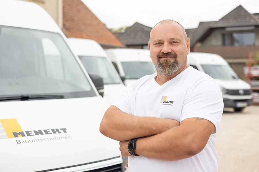 Leszek Paterek von Menert Bauunternehmen steht vor Firmenfahrzeugen