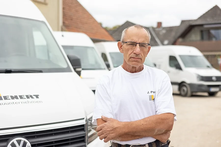 Jürgen Polzin steht vor mehreren weißen Transportern auf einem Firmenhof