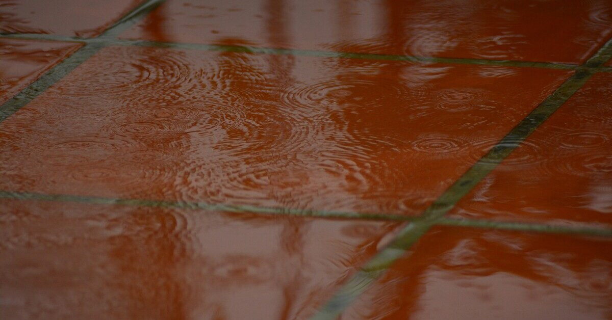 Wasser auf Bodenplatten nach Regen, Pfützenbildung auf Terrassenfliesen
