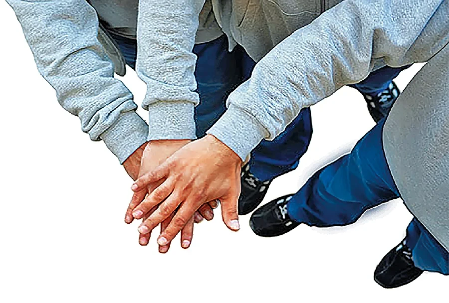 Mehrere Hände übereinander als Zeichen für Teamwork und Zusammenhalt