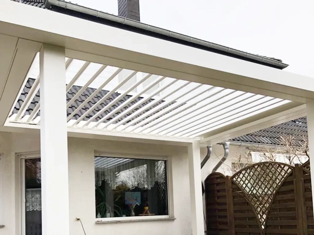 Modernes weißes Lamellendach als Terrassenüberdachung an einem Einfamilienhaus
