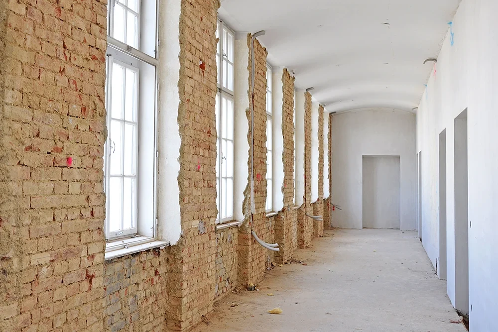 Sanierung einer Wohnung mit freigelegten Backsteinwänden und Fenstern