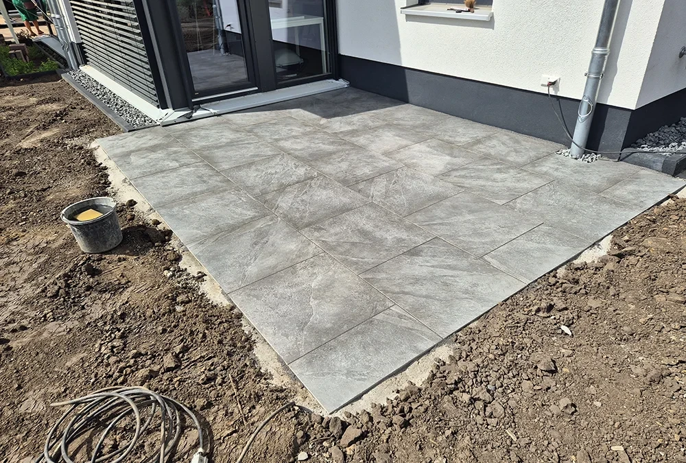 Mittrenga Terrasse mit modernen grauen Fliesen vor einem Haus