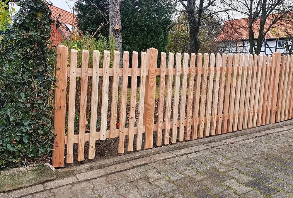 Moderner Holzzaun als Gartenzaun aus hellem Holz neben einer Straße