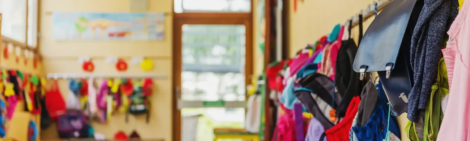 Bunte Kindergarderobe in einer Kita oder Grundschule mit Jacken und Rucksäcken