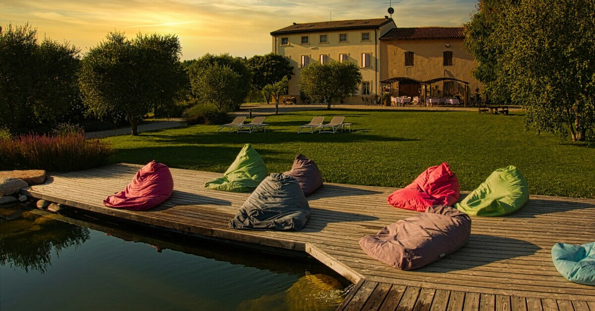 Schwimmteich mit Holzterrasse und Sitzsäcken im Garten bei Sonnenuntergang