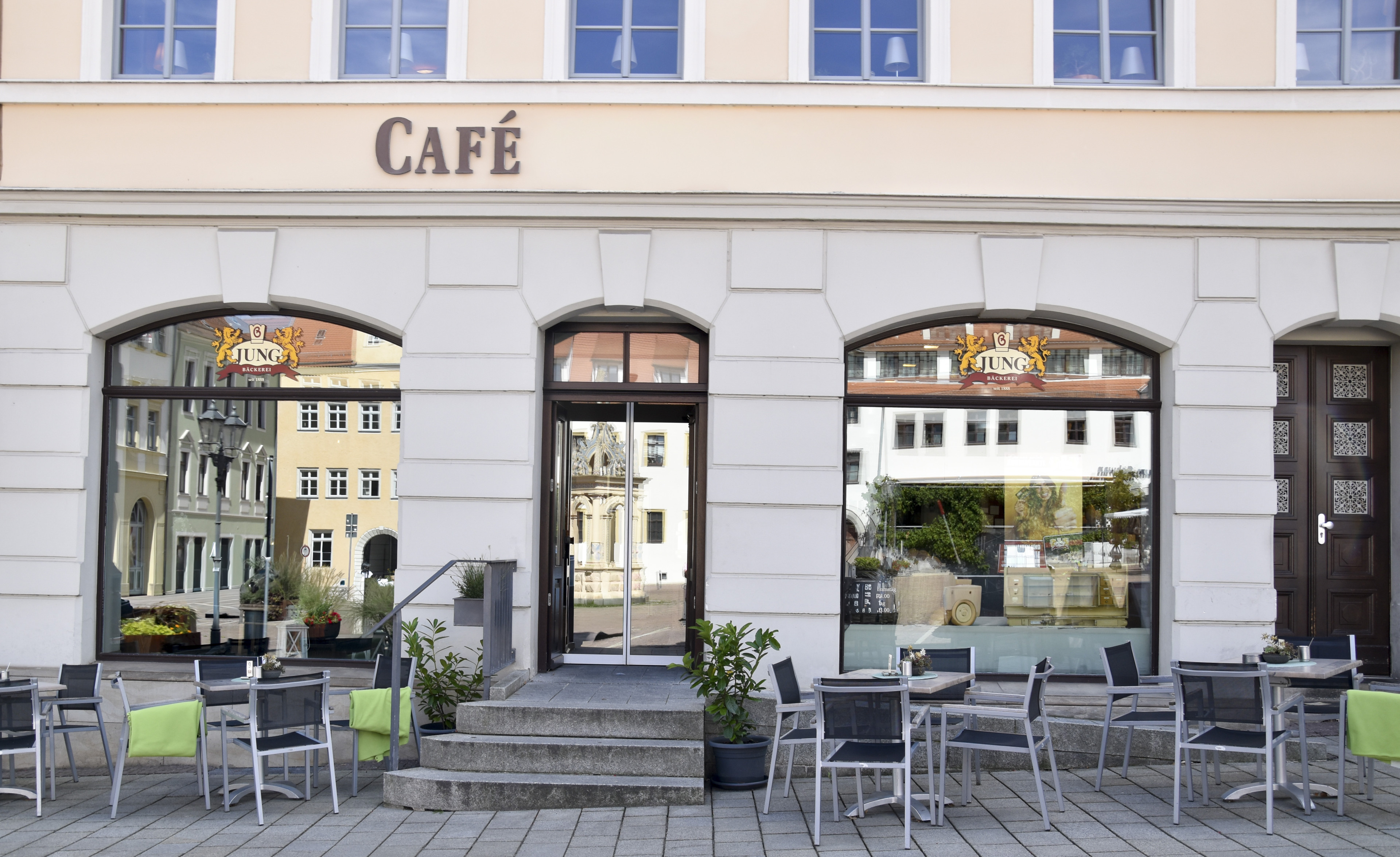 Eingang eines modernen Cafés mit Außenterrasse und Sitzgelegenheiten