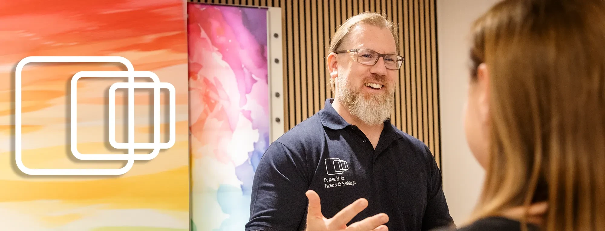 Dr. med. M. Au, Facharzt für Radiologie, im Gespräch vor farbigem Hintergrund
