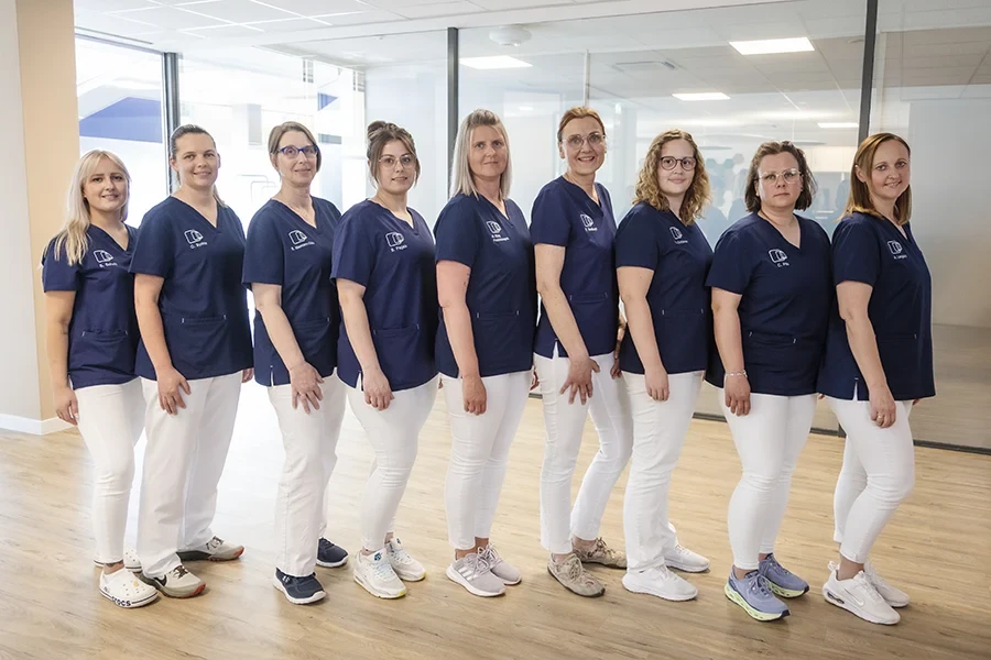 Teamfoto des medizinischen Fachpersonals in blauer und weißer Arbeitskleidung in einer modernen Praxis