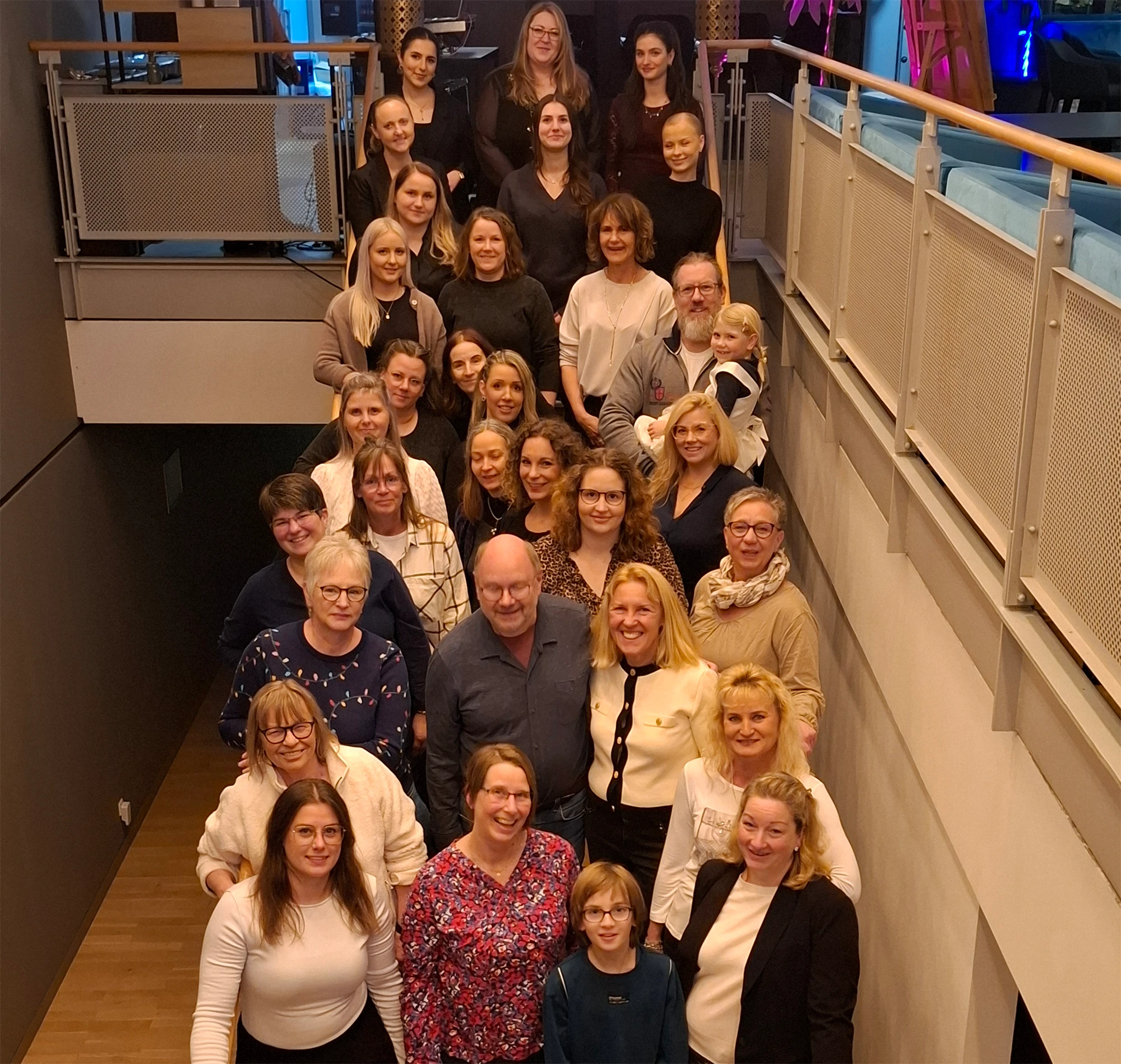 Gruppenfoto einer Weihnachtsfeier mit vielen fröhlichen Menschen auf einer Treppe