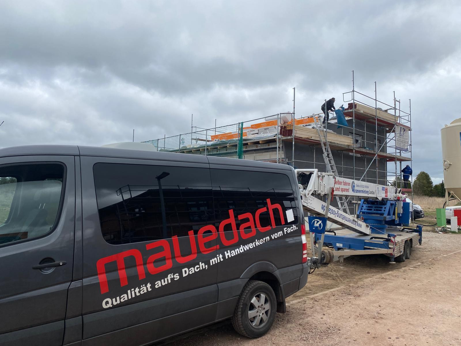 Maudach Transporter vor einer Baustelle mit Handwerkern auf dem Dach