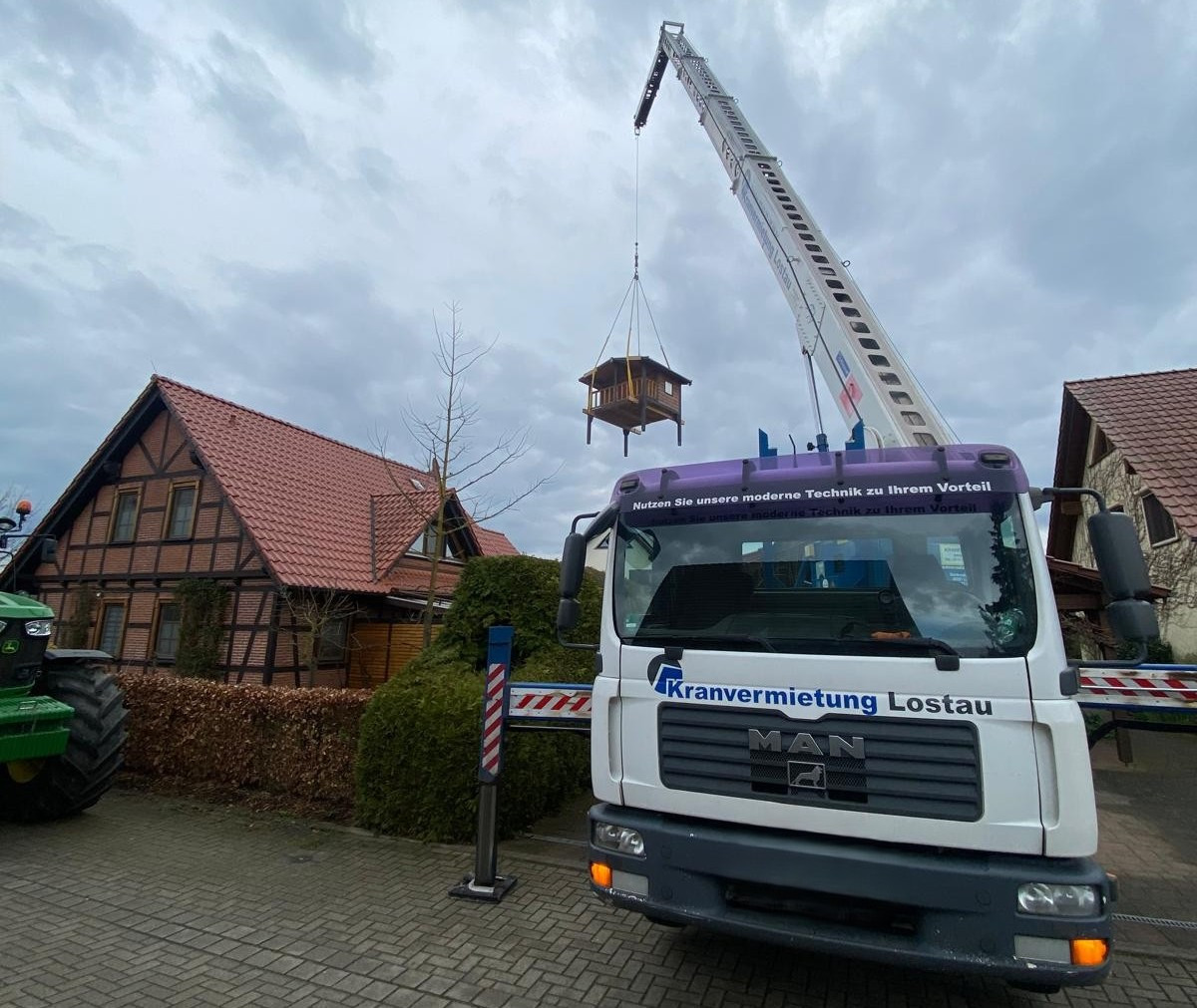 Kran hebt neues Mauerdach an Fachwerkhaus