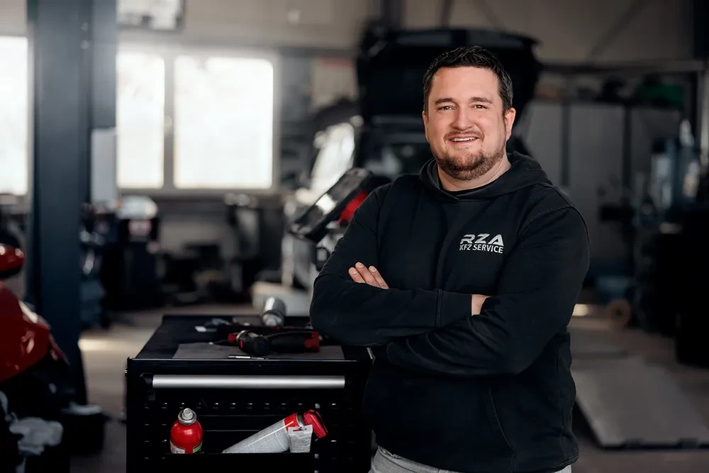 Portrait von Timo Schuhart in einer Kfz-Werkstatt mit verschränkten Armen