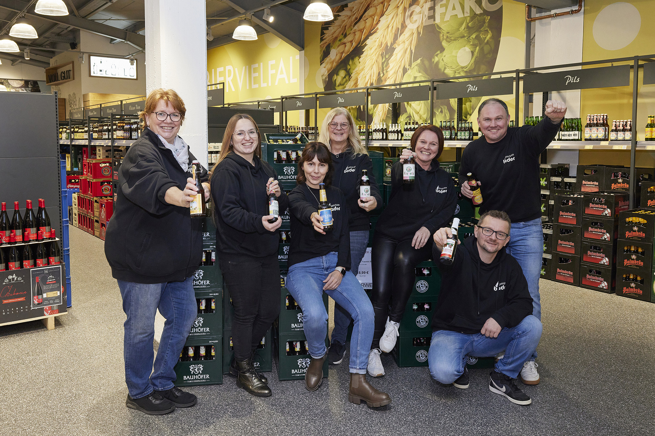 Gruppenfoto im Getränkemarkt mit Bauhöfer Bierkisten Gruppenfoto von Mitarbeitern in einem Getränkemarkt vor Bierkisten der Marke Bauhöfer