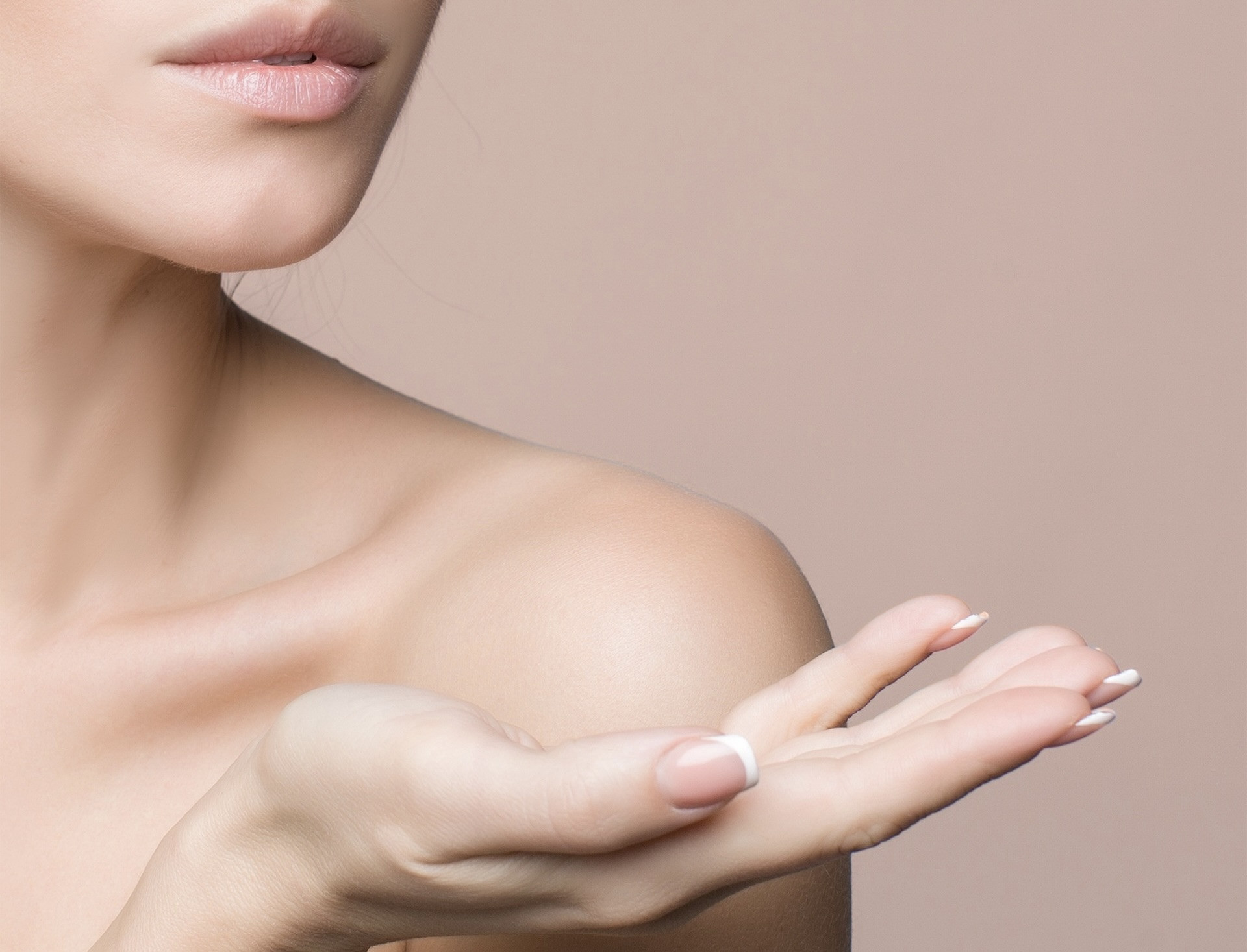 Beauty Nahaufnahme von weiblichem Gesicht, Lippen und gepflegter Hand auf neutralem Hintergrund