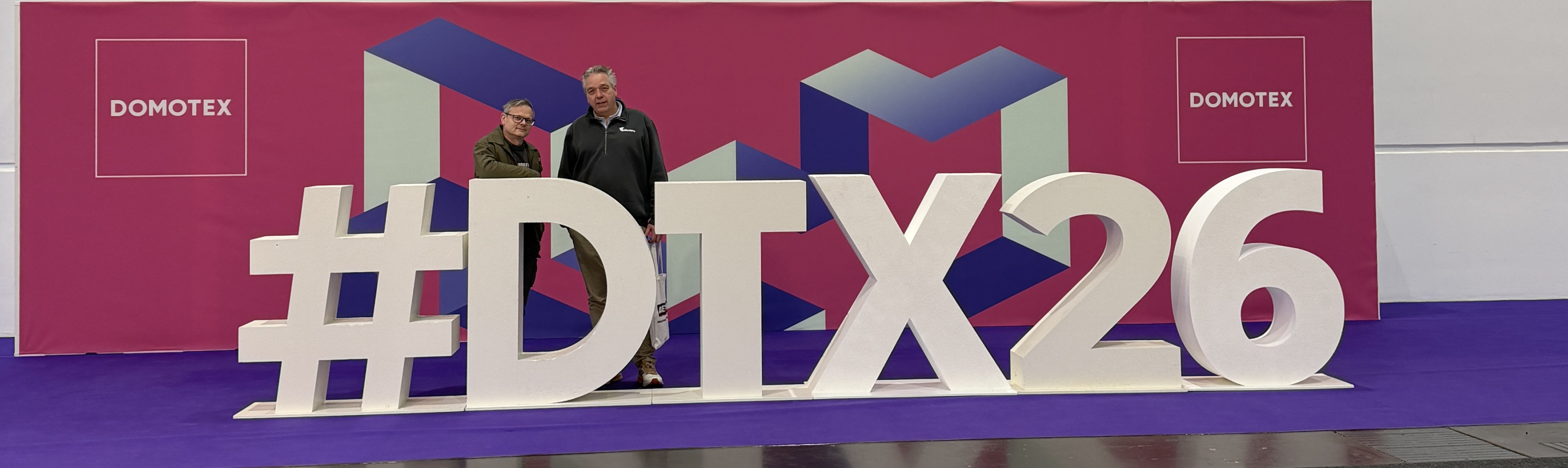 Große weiße Buchstaben DTX auf einer Messe mit modernem Hintergrund