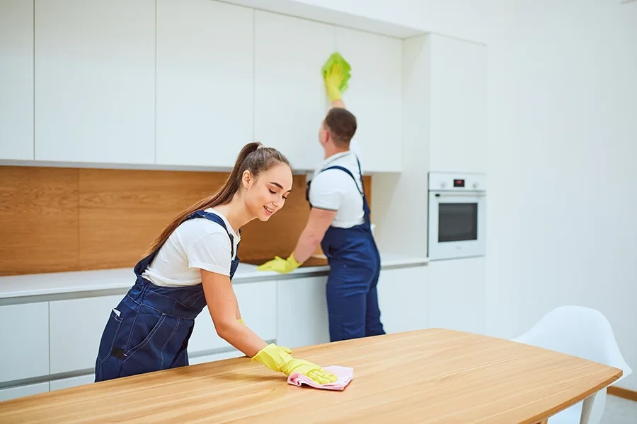 Mitarbeiter reinigen moderne Küche mit Handschuhen und Putzutensilien
