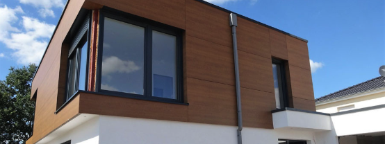 Fassadenarbeiten – moderne Holzverkleidung an Gebäudefassade Fassadenarbeiten an einem modernen Gebäude mit Holzverkleidung und Fenster