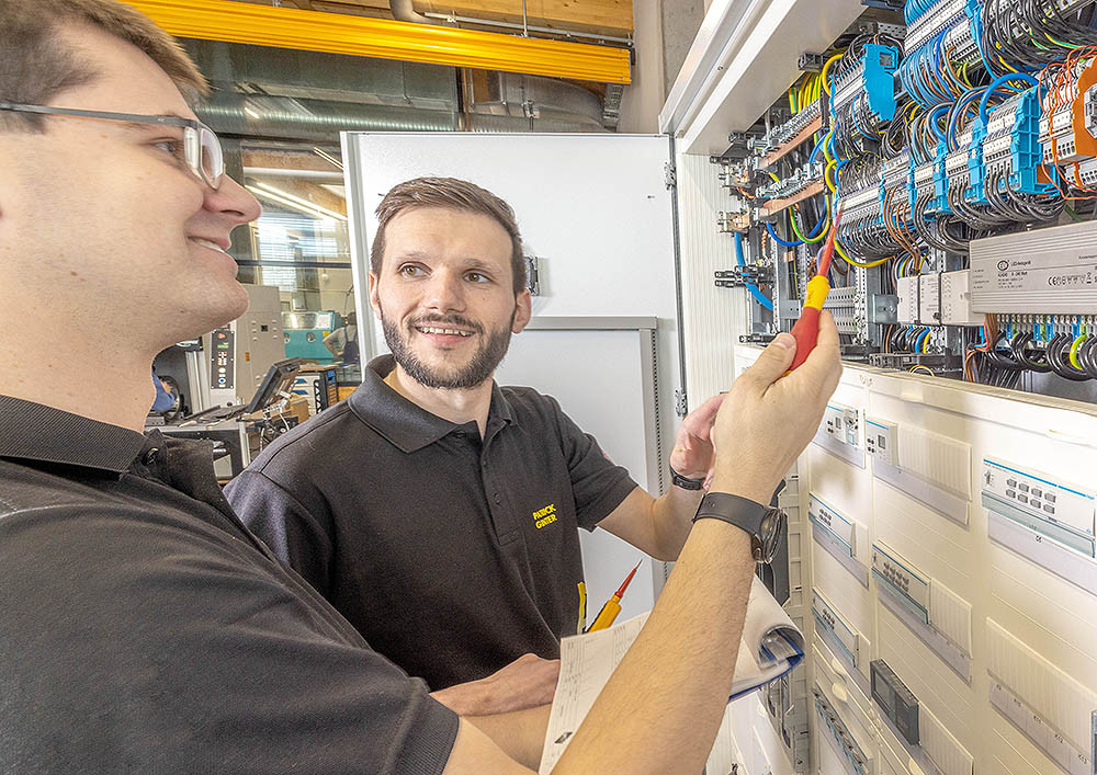 Zwei Elektriker bei der Arbeit an einem Schaltschrank in einer Werkstatt