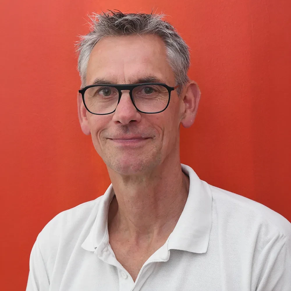 Portrait von Oliver Mais vor rotem Hintergrund