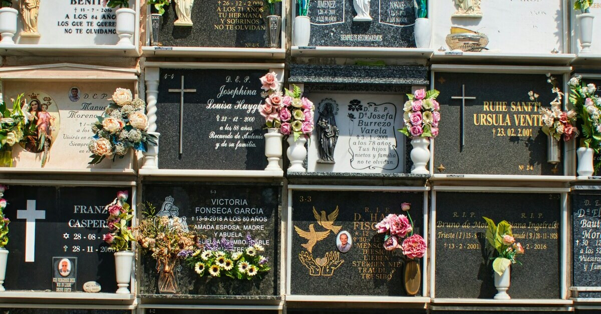 Mehrere Urnengräber mit Blumen und Gedenktafeln auf einem Friedhof