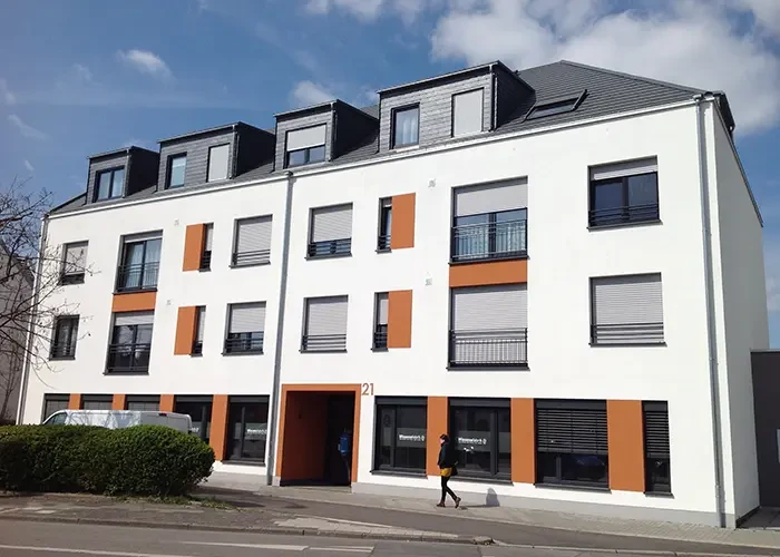 Modernes Wohngebäude mit weißer Fassade und orangefarbenen Akzenten, Hauptbild