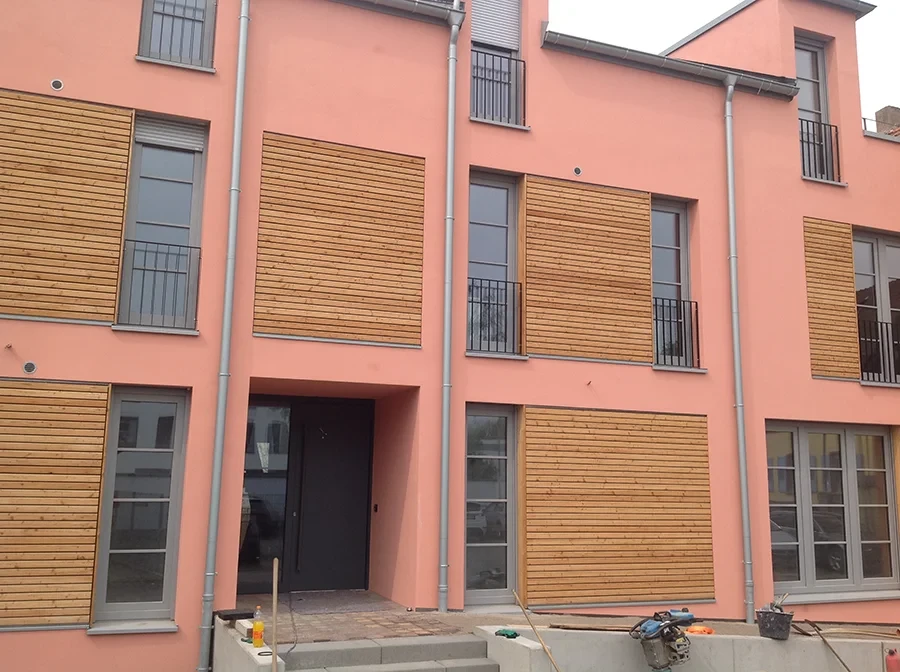 Moderne Hauswand mit Holzverkleidung und rosa Fassade