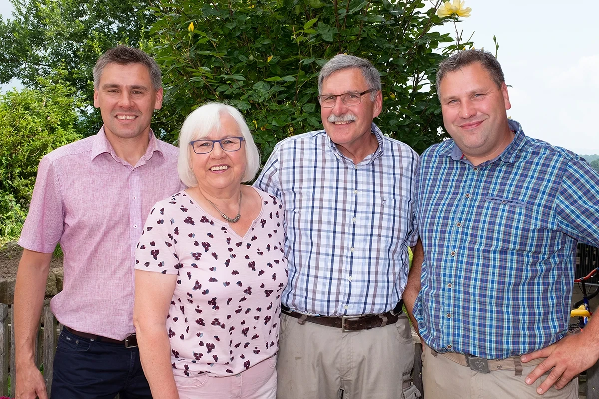 Teamfoto einer Gruppe von Menschen im Freien vor grünen Büschen