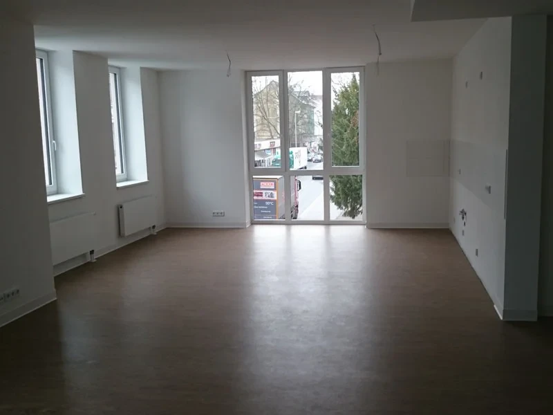 Umbauarbeiten in einem Mehrfamilienhaus, leerer Raum mit großen Fenstern und neuem Bodenbelag