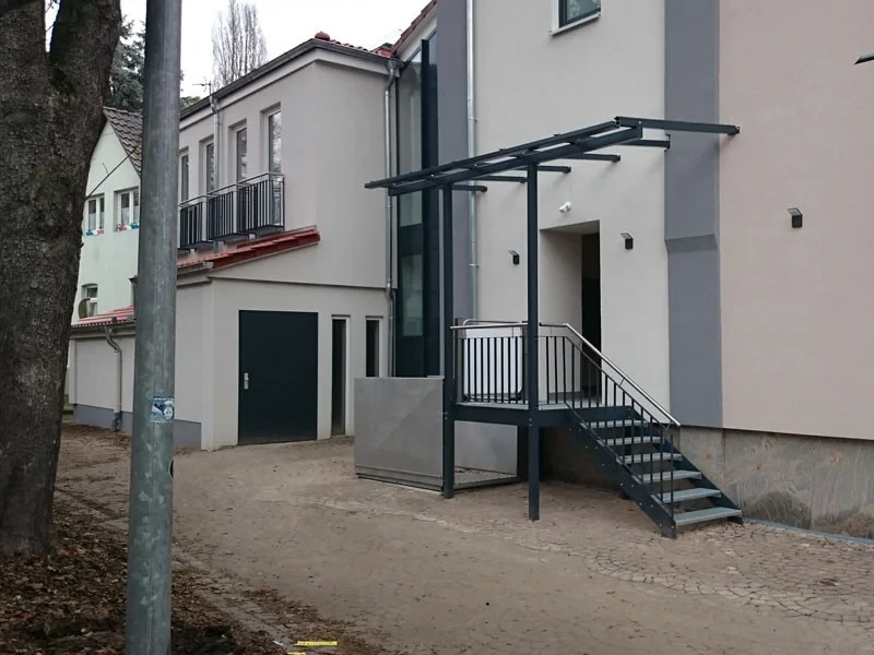 Umbauarbeiten an einem Mehrfamilienhaus mit modernem Eingangsbereich und Metalltreppe