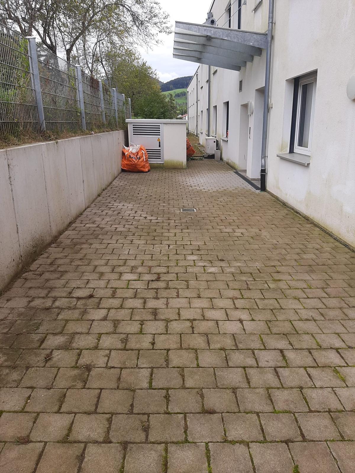 Ergebnis einer Steinreinigung: Sauberer gepflasterter Weg neben einem Gebäude, nachher Aufnahme, Mai 2025