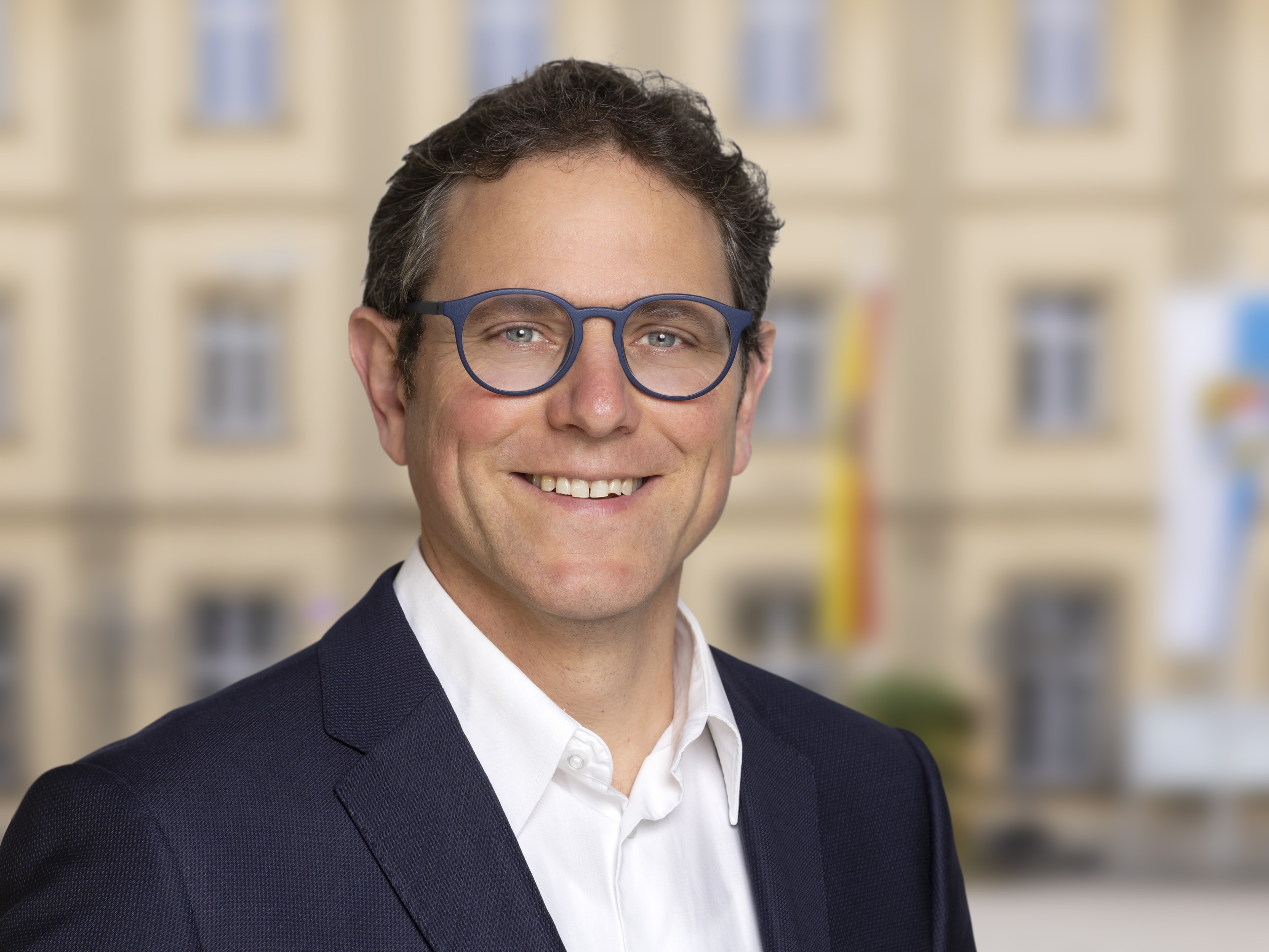 Porträtfoto einer Person mit dem Namen Heilig im Anzug vor einem Gebäude
