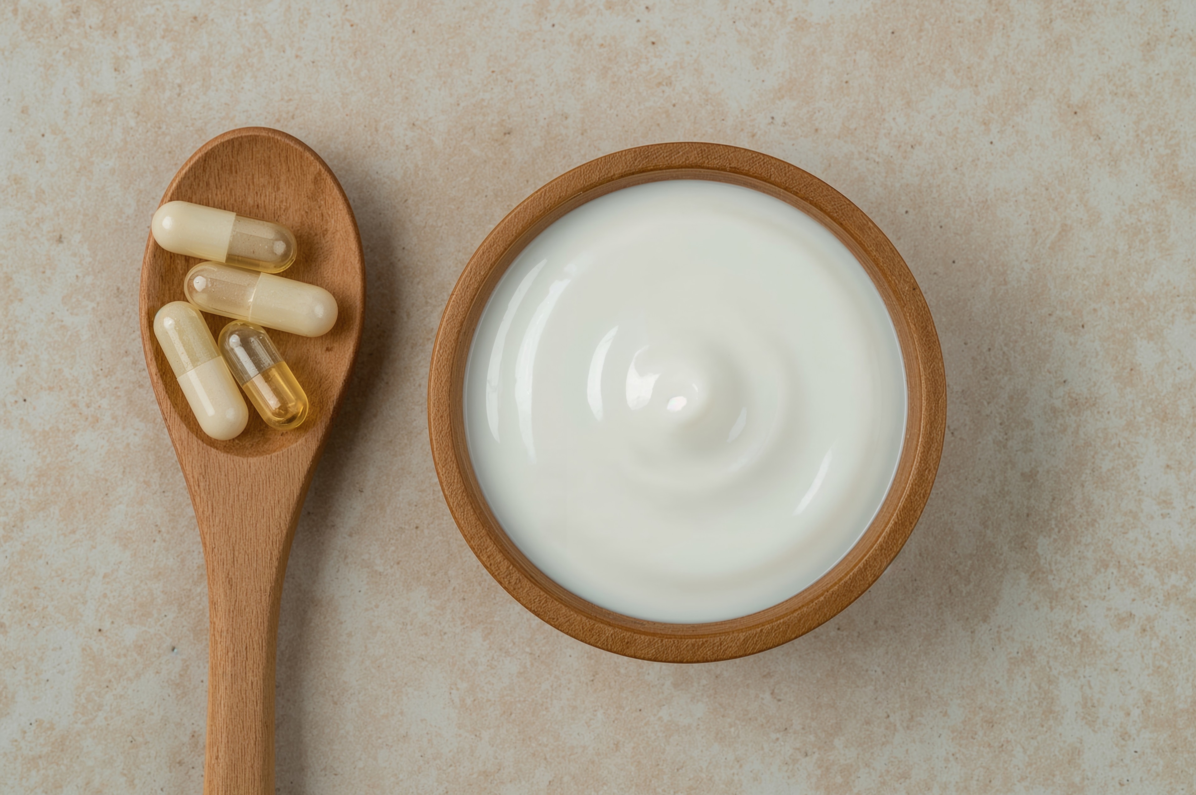 Naturjoghurt und Nahrungsergänzungsmittel – gesunde Ernährung und Probiotika Naturjoghurt in einer Holzschale mit Nahrungsergänzungsmitteln auf Holzlöffel, gesunde Ernährung und Probiotika