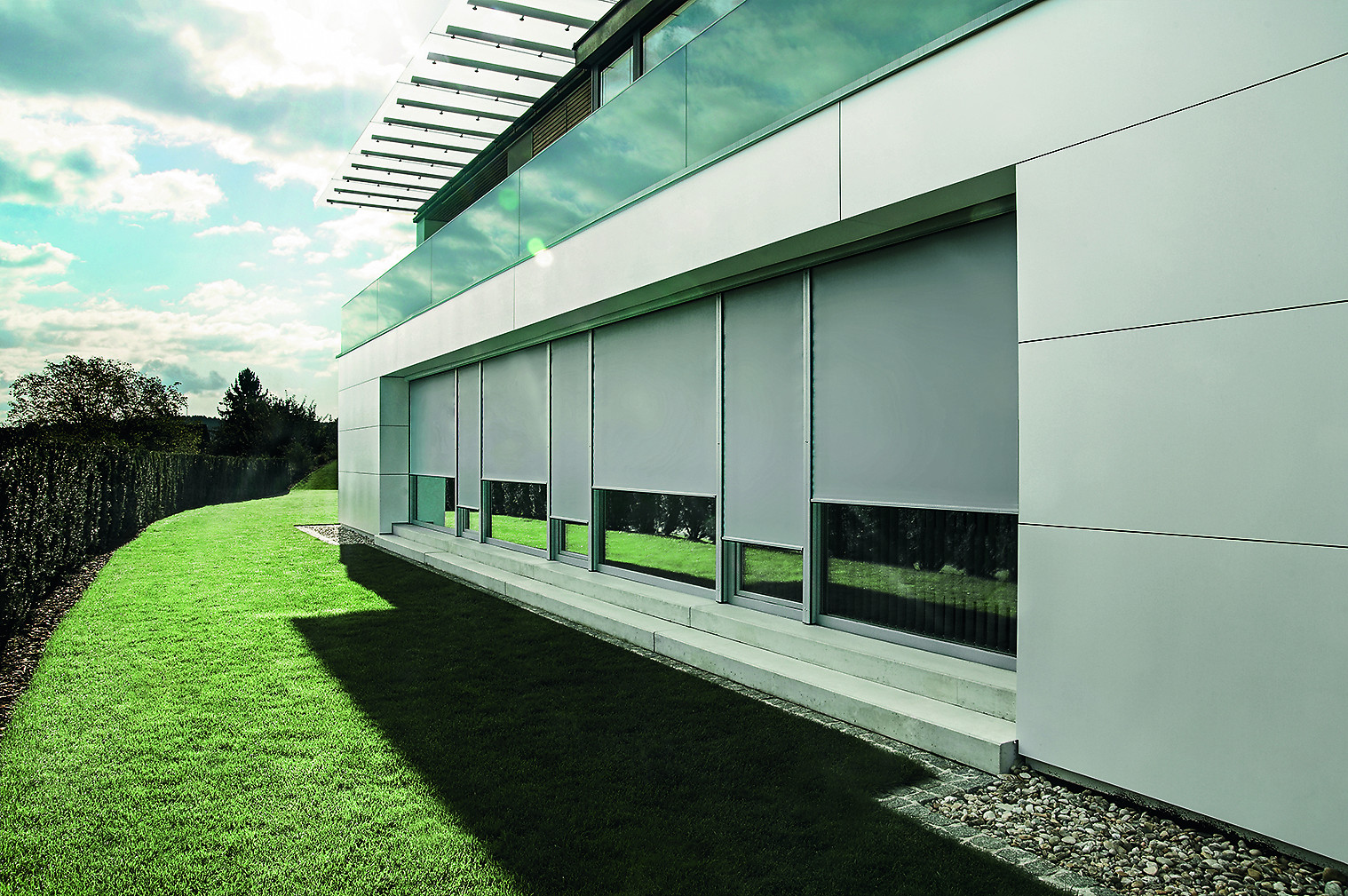 Moderne Außenansicht eines Gebäudes mit großen Fenstern und heruntergelassenen Sonnenschutz-Rollos