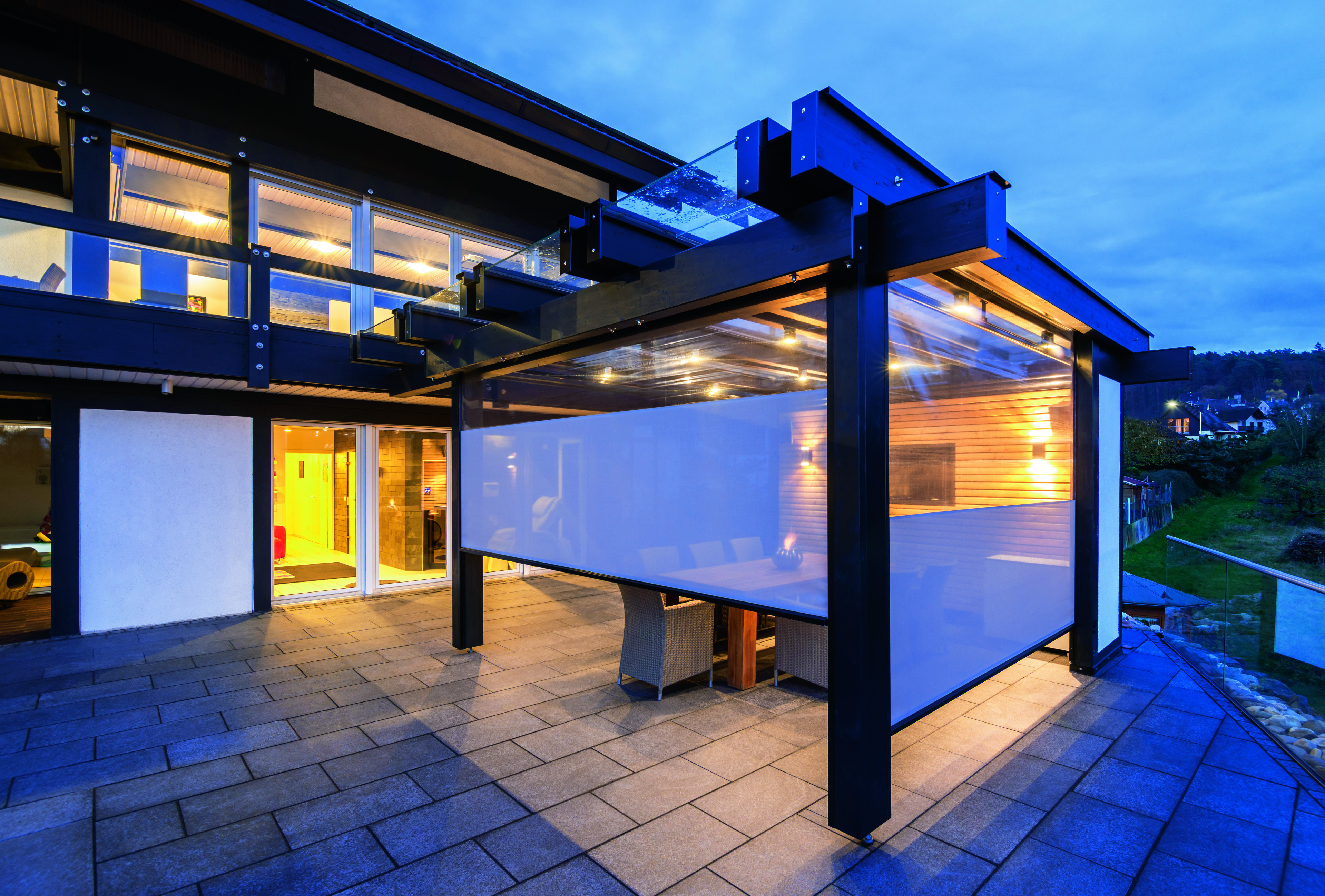 Moderne Terrasse mit Glasüberdachung und Sichtschutz bei Objekt 413 SRF1666 am Abend