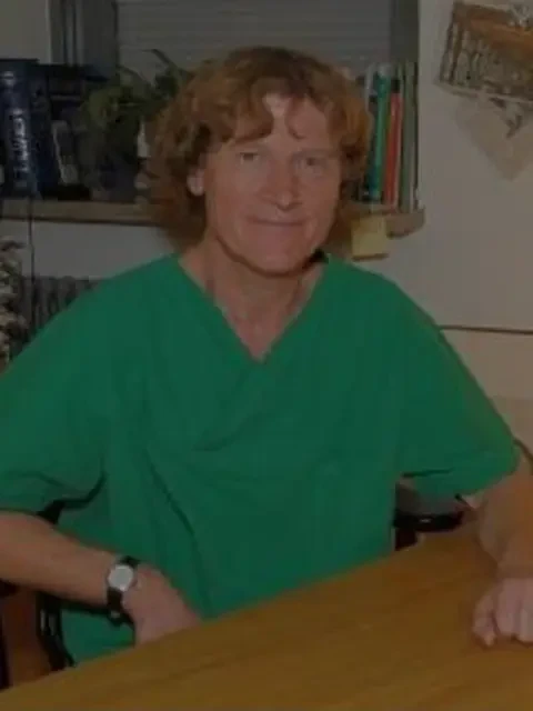 Dr. Schulz in grüner Arbeitskleidung am Schreibtisch