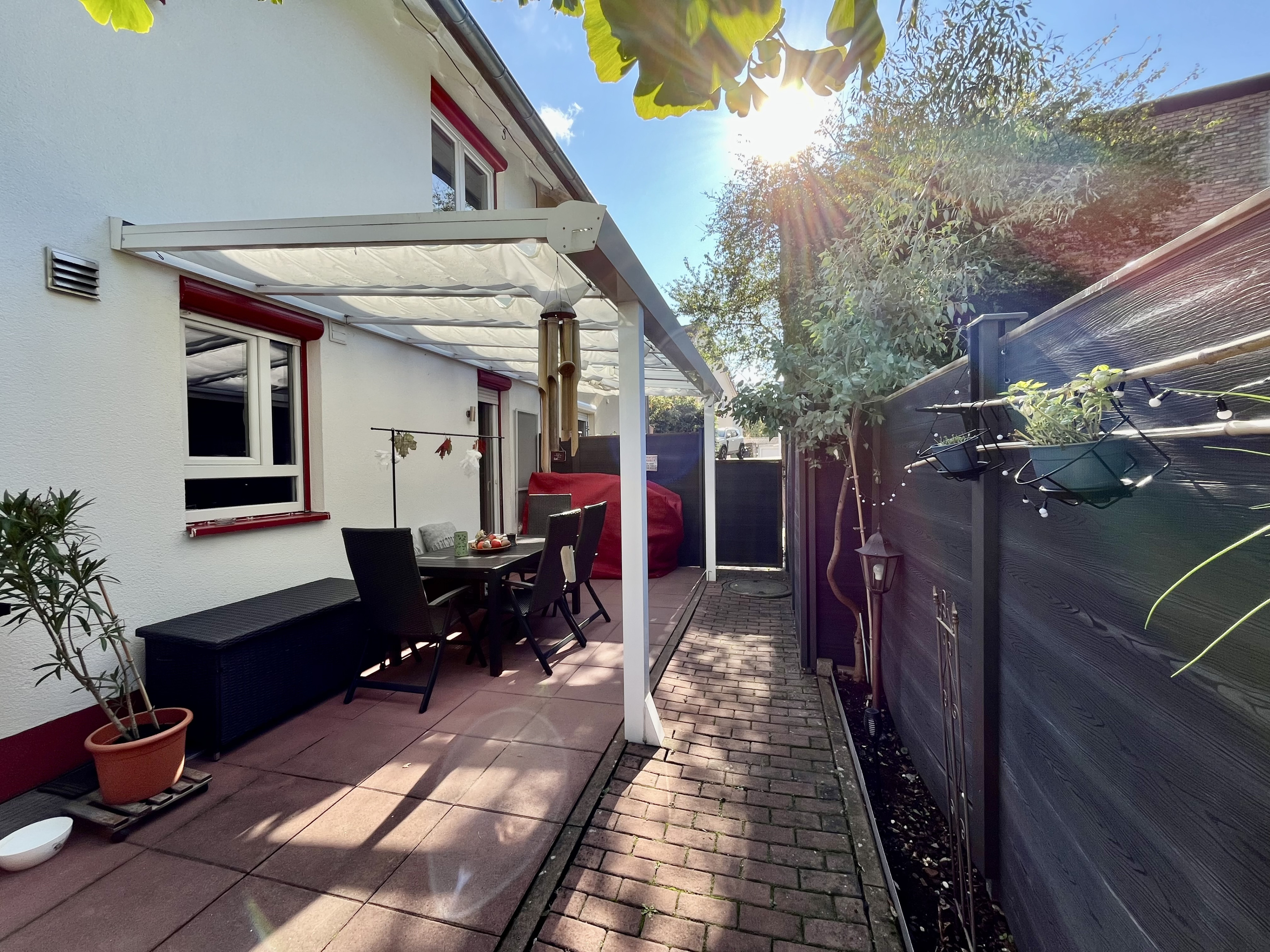Überdachte Terrasse mit Sitzgruppe an einem Einfamilienhaus bei Sonnenschein