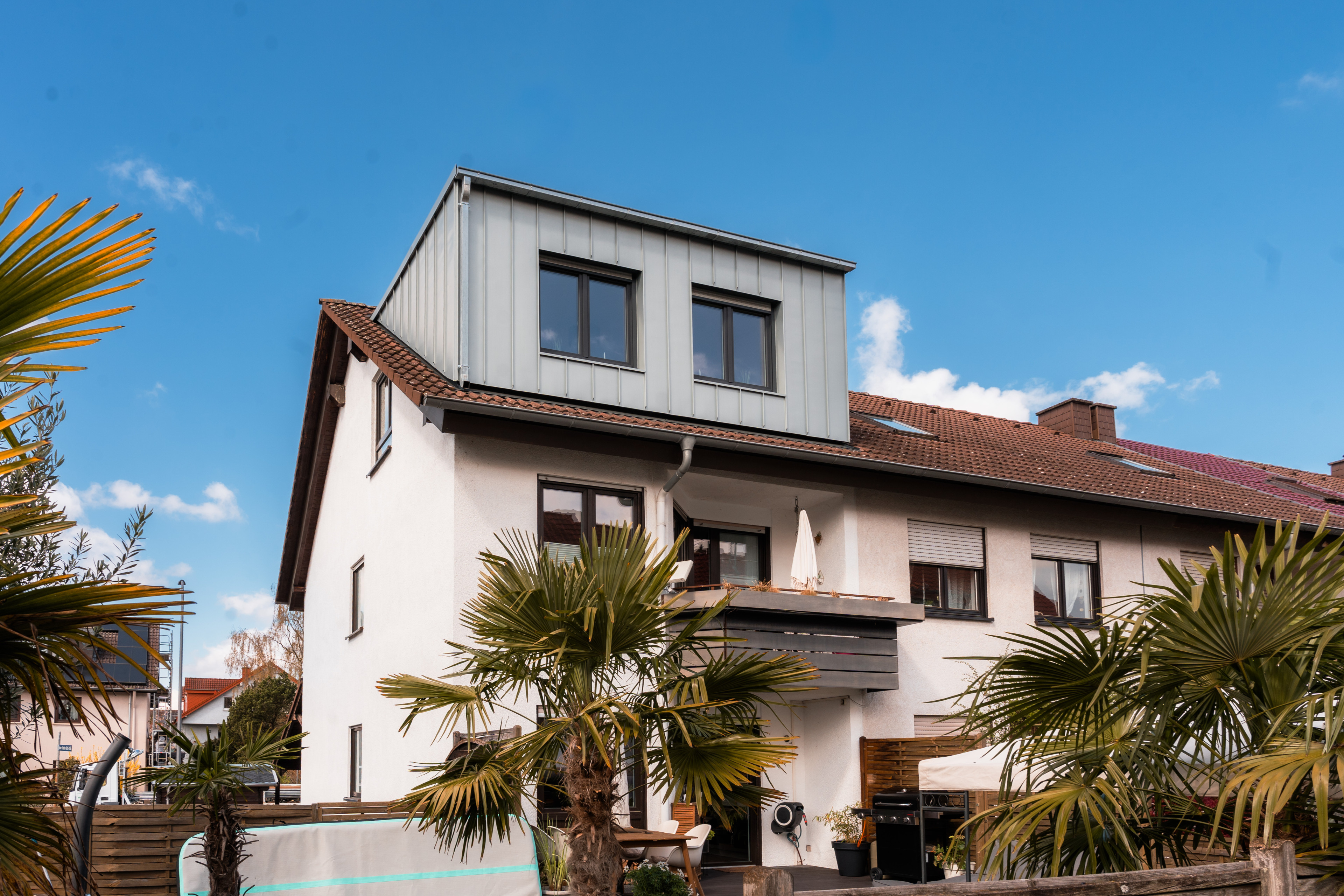 Modernes Einfamilienhaus mit Dachaufstockung und Balkon an einem sonnigen Tag