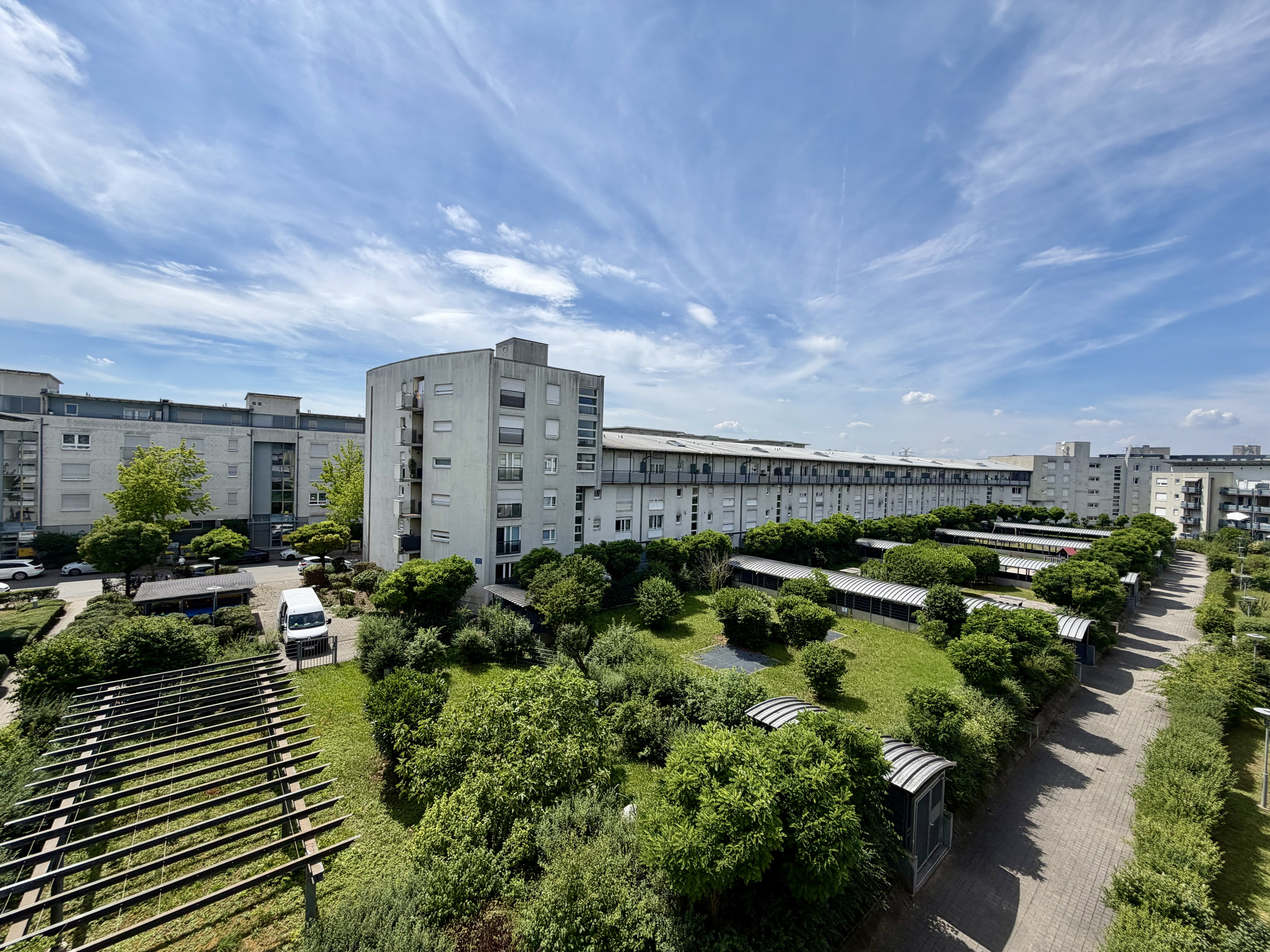 Modernes Wohngebäude mit begrüntem Innenhof und blauem Himmel