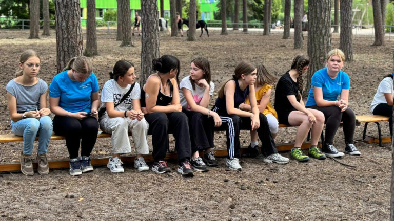 Jugendliche im Wald auf einer Bank sitzend Gruppe von Jugendlichen sitzt im Wald auf einer Bank.