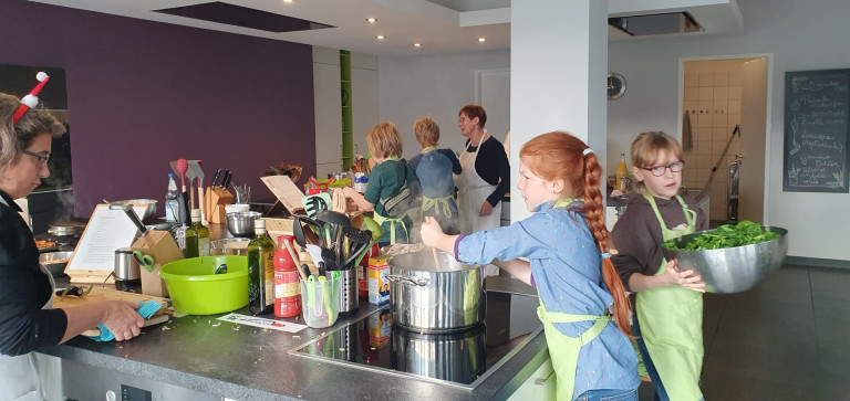 Kinder und Erwachsene beim gemeinsamen Kochen in einer modernen Küche