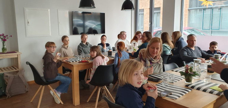 Gruppe von Menschen bei einem Treffen oder Workshop in einem modernen Raum mit großen Fenstern und Holztisch