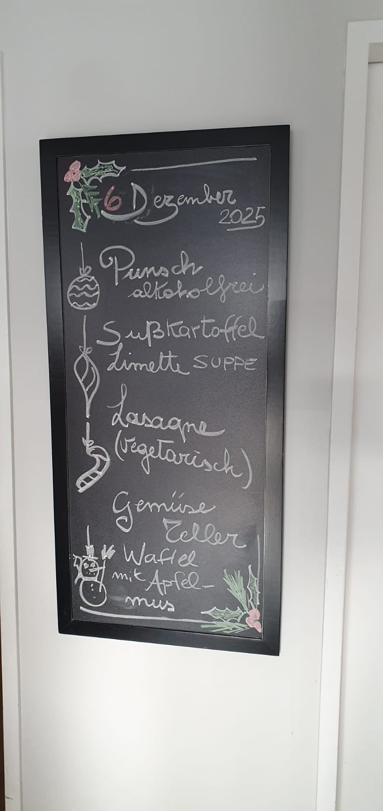 Speisekarte auf einer Kreidetafel mit alkoholfreiem Punsch, Süßkartoffel-Limetten-Suppe, vegetarischer Lasagne, Gemüseteller und Waffel mit Apfel.