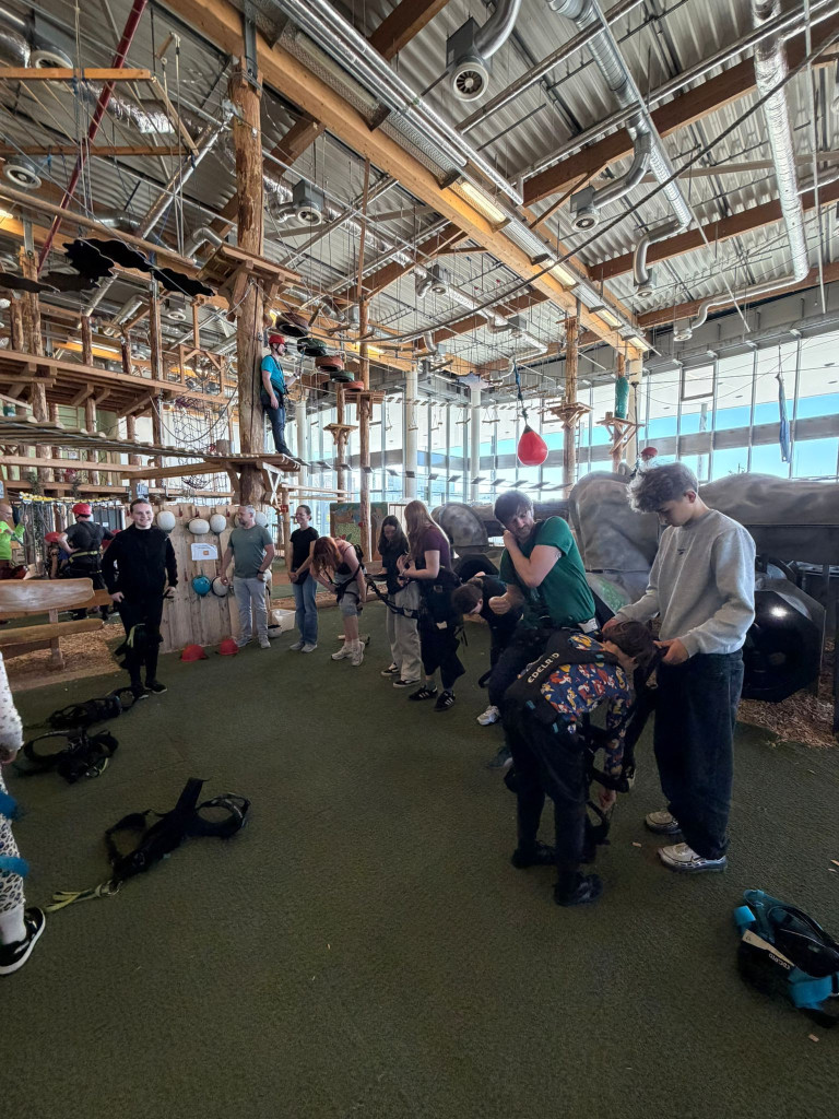 Gruppe bereitet sich im Indoor-Kletterpark auf den Kletterparcours vor