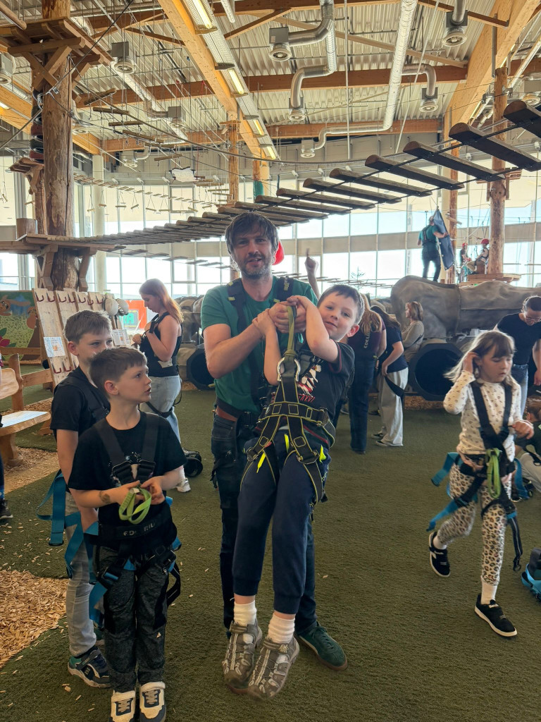 Kinder und Erwachsene im Indoor-Kletterpark mit Kletterausrüstung