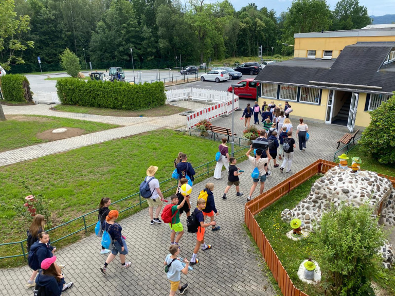 Kinder und Betreuer auf einem Schulhof bei sommerlichem Ausflug Kindergruppe mit Betreuern beim Ausflug auf einem Schulhof im Sommer