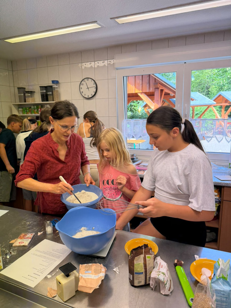 Backen mit Kindern in der Küche – gemeinsames Zubereiten von Teig und Zutaten Kinder und Erwachsene beim gemeinsamen Backen in einer Küche, verschiedene Zutaten und Schüsseln auf dem Tisch