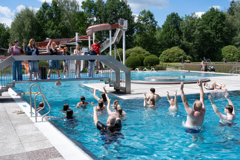 Gruppenaktivität und Spaß im Freibad Seifhennersdorf mit moderner Wasserrutsche Gruppenaktivität im Freibad Seifhennersdorf mit Wasserrutsche und Teilnehmern im Wasser