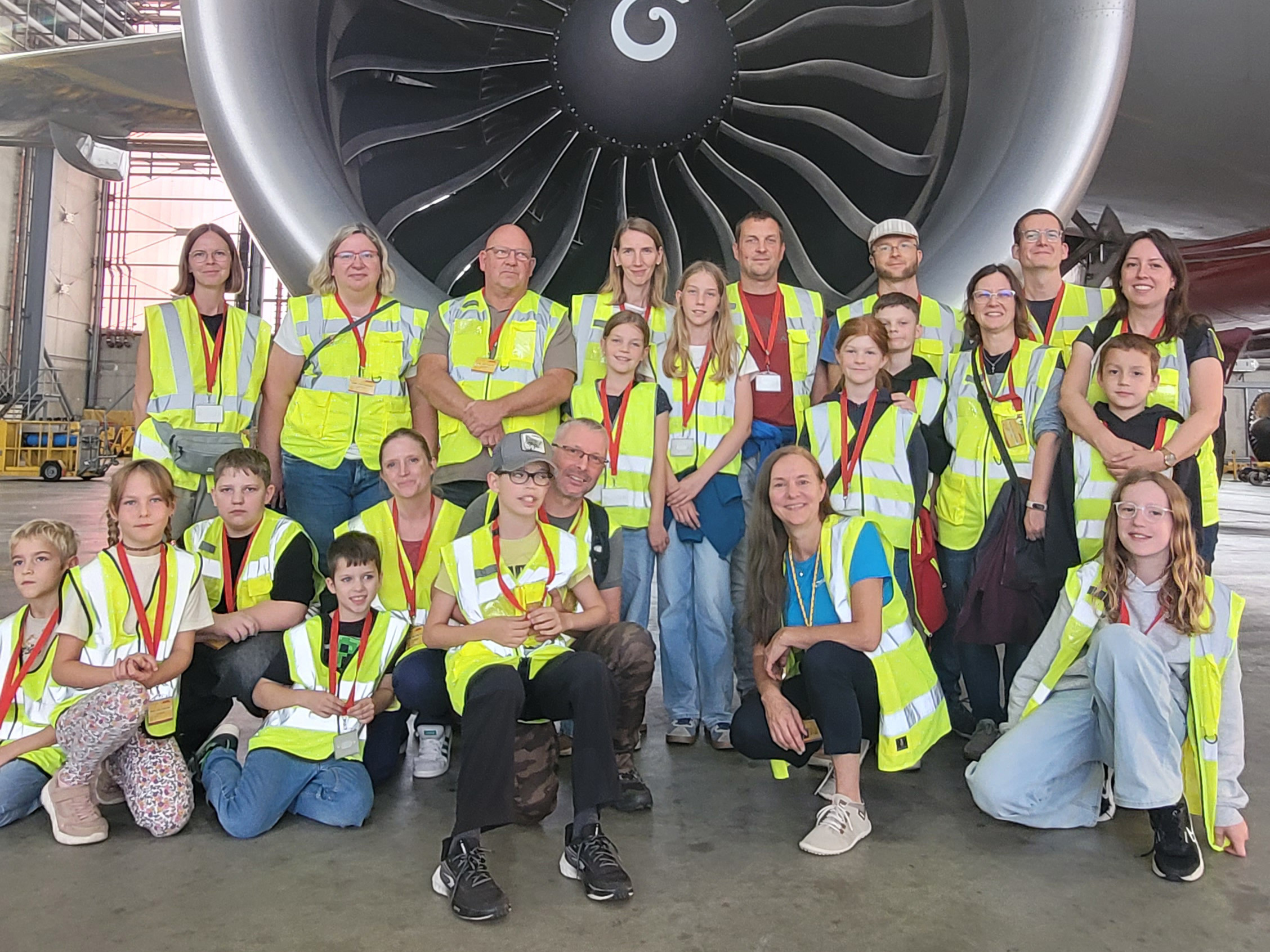 Gruppe von Menschen mit Warnwesten vor einem großen Flugzeugtriebwerk bei einer Werksbesichtigung