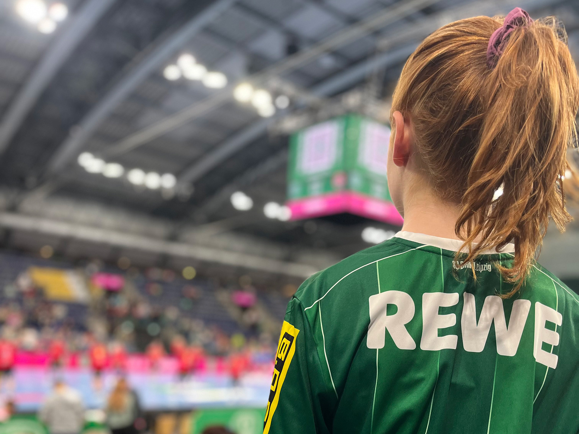 Handballspiel in einer Halle mit Fokus auf Spielerin im grünen Trikot beim Pink Oktober Event